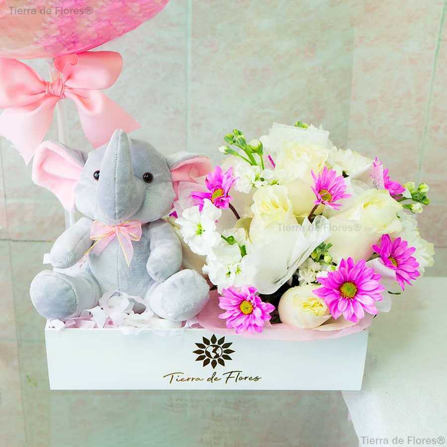 arreglo floral para nacimiento de niÃ±a hay un elefante con lazo rosa y flores blancas y rosadas