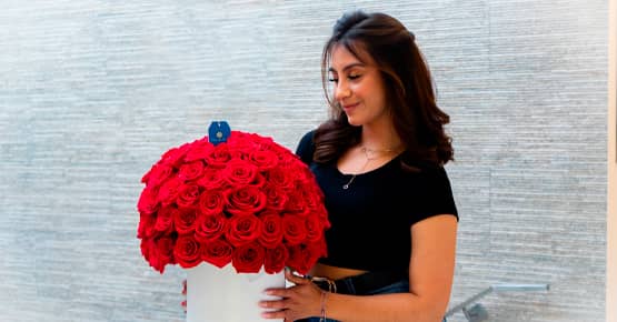 Mujer joven sostiene un arreglo de rosas rojas